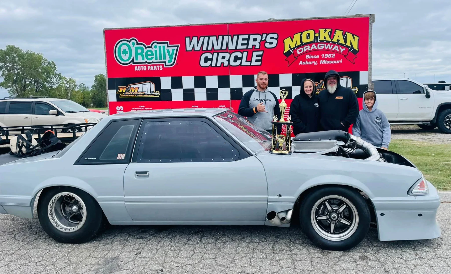 Silver Fox-body Mustang at a drag racing winner's circle