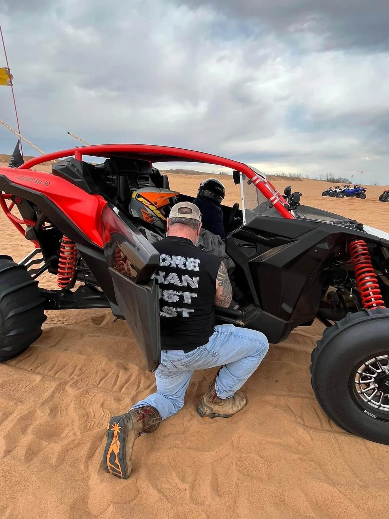 Red side-by-side and its driver in the dunes