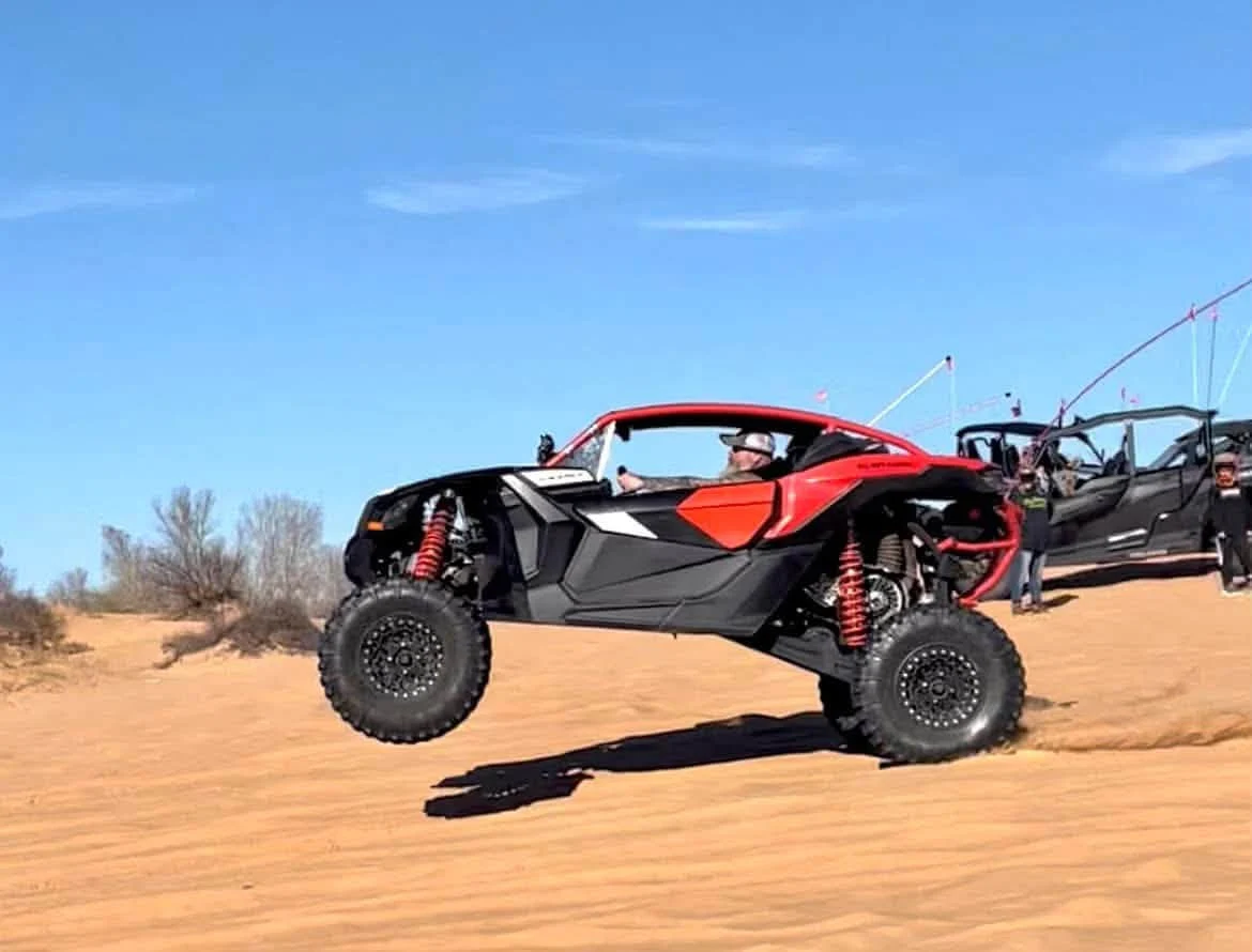 Red off-road side-by-side driving across sand dunes